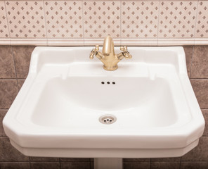 Fototapeta premium White ceramic sink with bronze faucet against the wall with tiles