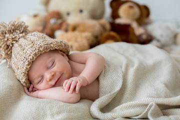 Little newborn baby boy, sleeping with teddy bear at home in bed © Tomsickova