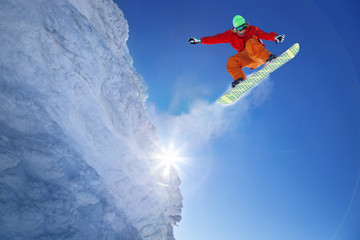 Snowboarder jumping against blue sky