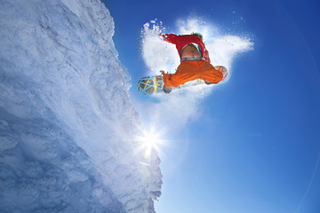 Snowboarder jumping against blue sky