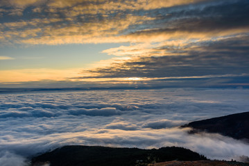 Fototapeta na wymiar Cloud inversion from a mountain top - beautiful autumn landscape with thick blanket of rolling clouds at sunrise