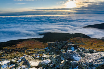 Cloud inversion from a mountain top - beautiful autumn landscape with thick blanket of rolling clouds at sunrise