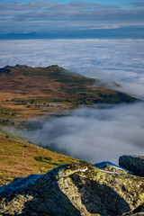 Cloud inversion from a mountain top - beautiful autumn landscape with thick blanket of rolling clouds at sunrise