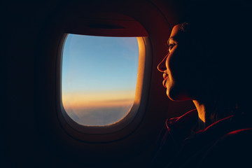 Fototapeta premium woman looking at sky with clouds from the airplane window. sunset with a height of 10 000 km. woman face close up