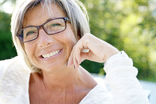 Cheerful mature woman with eyeglasses relaxing outside