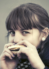 Happy teen girl eating a burger