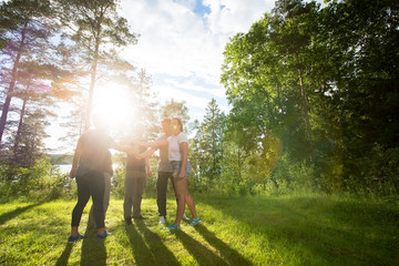 Coworkers Stacking Fists While Standing In Forest On Sunny Day
