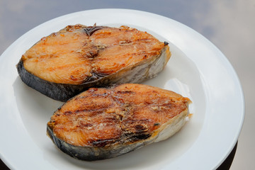 A grilled mackerel fish on white plate is a one of the Malaysian people favorite dish