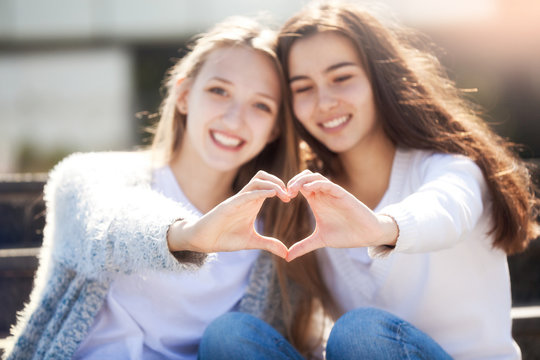 Two Girls Holding Hands in Shape of Heart