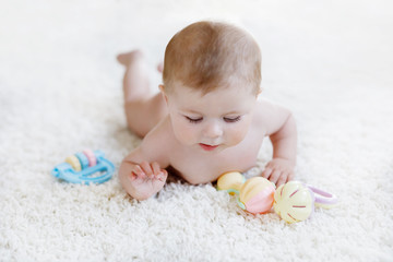 Cute baby girl playing with colorful pastel vintage rattle toy