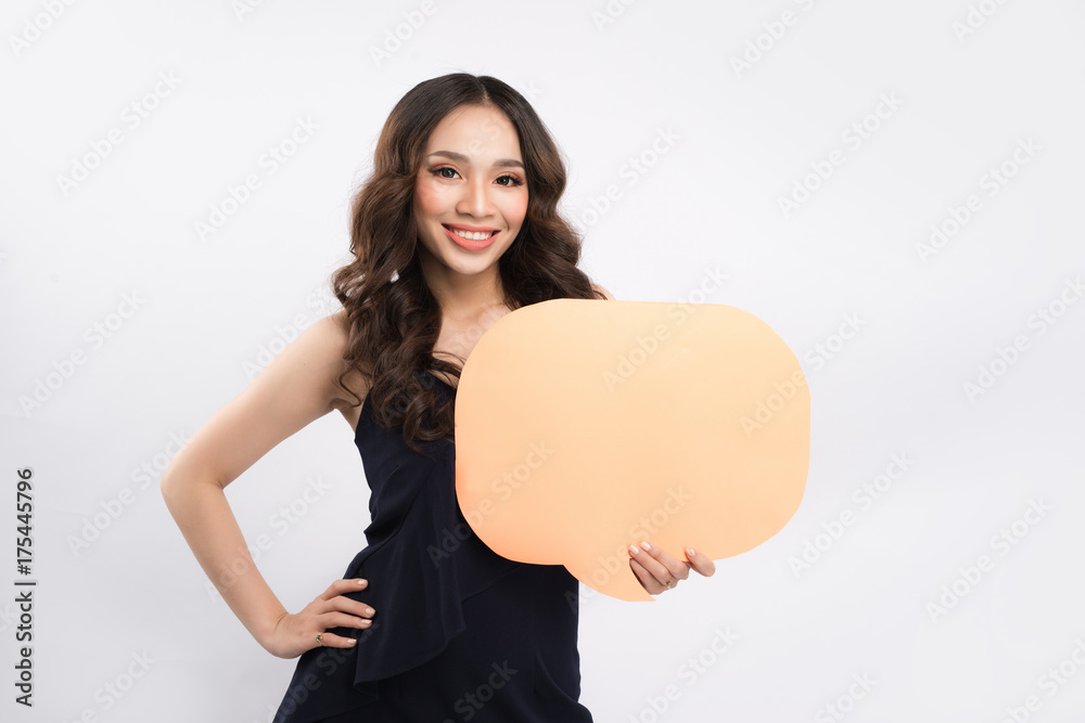 Wall mural Smiling young woman holding empty speech bubble while standing on blue background