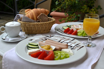 Table with nicely served American breakfast - sausages, vegetables, croissants