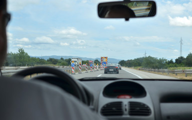 Man driving a car on a highway with other vehicles blurred in front of him