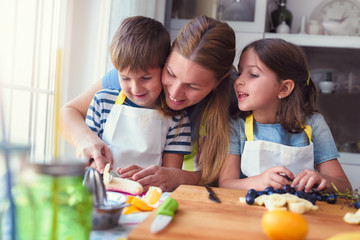 Cute kids with mother preparing a healthy fruit snack in kitchen 