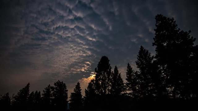 time lapse of orange full moon in Montana with clouds