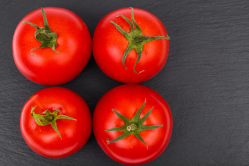 Ripe red tomatoes on black stone plate