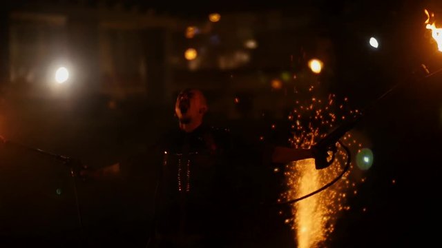 The stuntman plays with the flamethrower at night.
