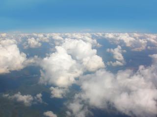 View from airplane window. White clouds above the land.