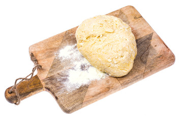 Ball of pizza dough on wooden kitchen cutting board with dusting of flour