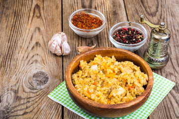 Pilaf with meat and carrots in wooden bowl on the table
