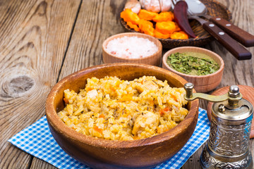 Pilaf with meat and carrots in wooden bowl on the table