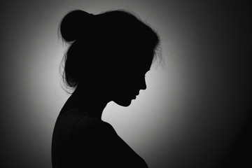 silhouette of the face profile of an unknown sad woman, female in depression bowed her head