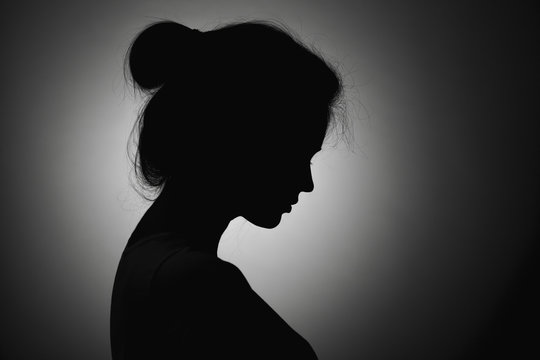 Silhouette of a thoughtful sad woman with hand near her forehead