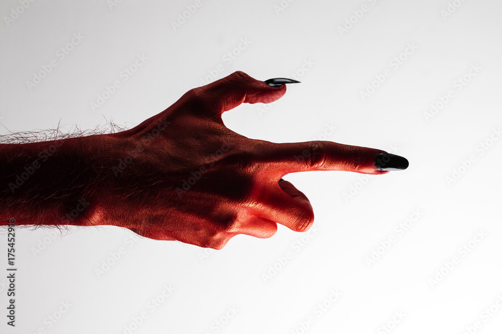 Wall mural halloween red devil monster hand with black fingernails against a plain background