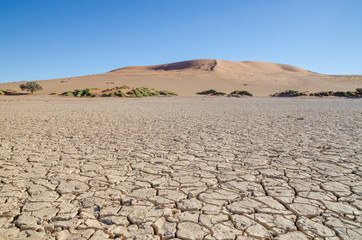 Beautiful towering red sand dunes and dry cracked clay surface at famous Sossusvlei in Namib desert, Namibia, Africa