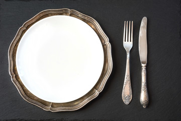 Vintage dish with silverware on slate background. Table place setting.
