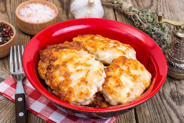 Schnitzels of meat in bowl on wooden table