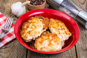 Schnitzels of meat in bowl on wooden table