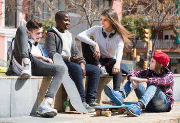 Fototapeta premium girl and three boys hanging out outdoors and discussing something