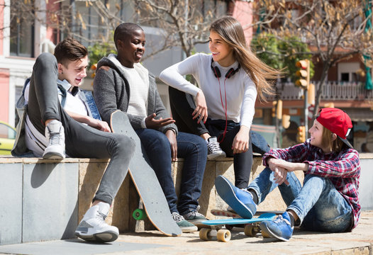 girl and three boys hanging out outdoors and discussing something
