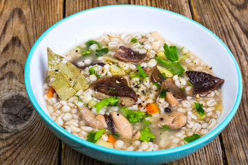 Vegetarian soup with mushrooms and pearl barley for lunch on wooden table