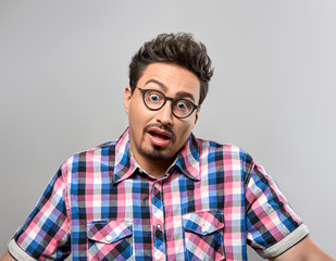 Handsome young man Thinks Idea, Crazy. Portrait Hipster Nerd Loser guy in Trendy shirt, Glasses. Brunette Bearded Emotional man, Stylish fashion Hairstyle on gray background. Blue Eyes