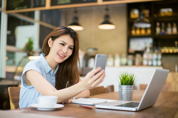 Beautiful Asia woman using laptop and smart phone at cafe