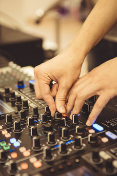 Close-up hands of soundman working with audio mixing board. 