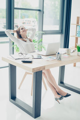 Relaxed successful assistant is resting at her work spot and dreams of holiday which is coming, in formal wear, skirt, nice black shoes, hands are behind head, chill mode, nice light interior
