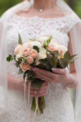 Hands of bride holding a bouquet of roses