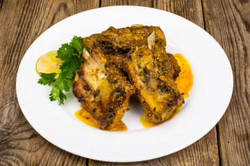 Spicy meat ribs in mustard sauce on wooden table