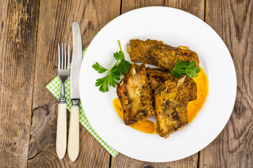 Spicy meat ribs in mustard sauce on wooden table