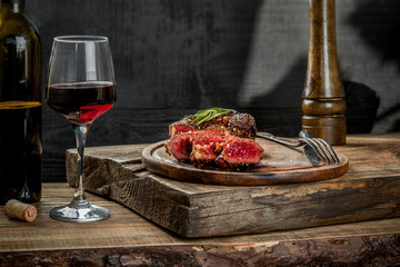 Grilled ribeye beef steak with red wine, herbs and spices on wooden table