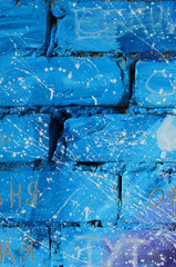 The texture of the old brick wall, painted in blue and purple colors with carelessly spaced white...