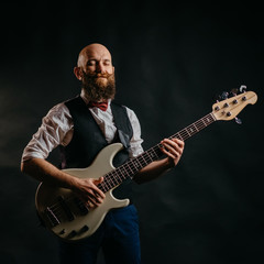 adult bearded man enthusiastically playing guitar on a black background
