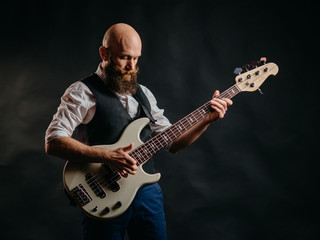 Obraz premium adult bearded man enthusiastically playing guitar on a black background