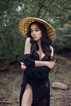 young sexy Vietnamese girl in a straw hat in a tropical forest