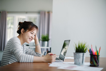 Beautiful young Asia woman working with laptop at home office