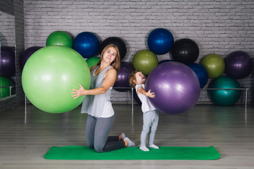 Mother and baby girl do exercises together in the gym