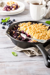 Coconut crumble in cast iron pan with fresh apples and blueberry. Healthy food concept with copy space.